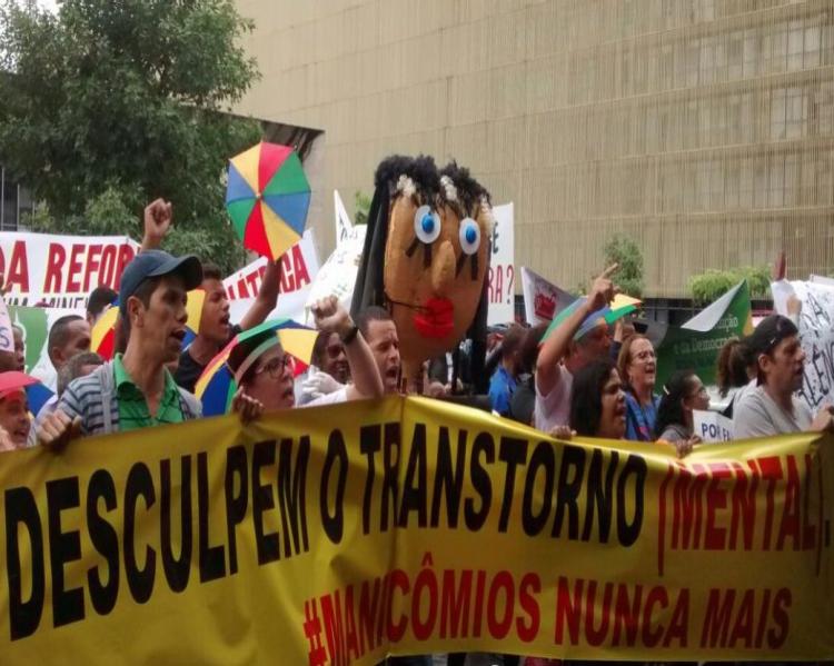 Manifestantes levam uma faixa amarela em primeiro plano, onde se lê: 'Desculpe o transtorno. #Manicômios nunca mais' 