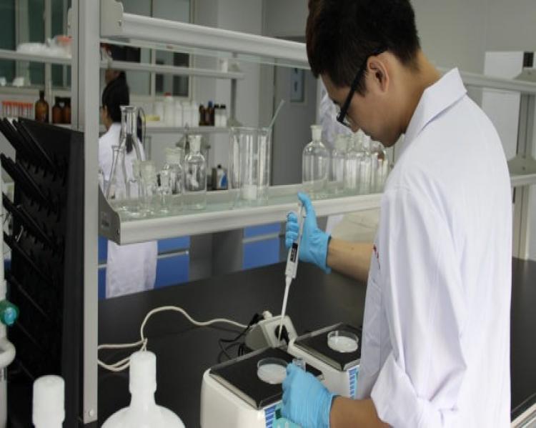 Homem de jaleco branco e luvas verdes, em um laboratório