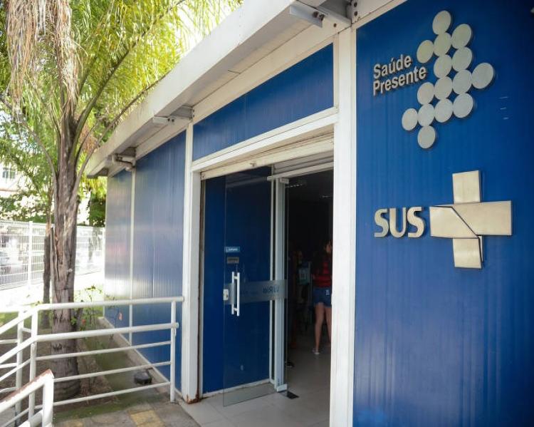 Fachada de unidade de saúde, com parede azul e a marca do SUS